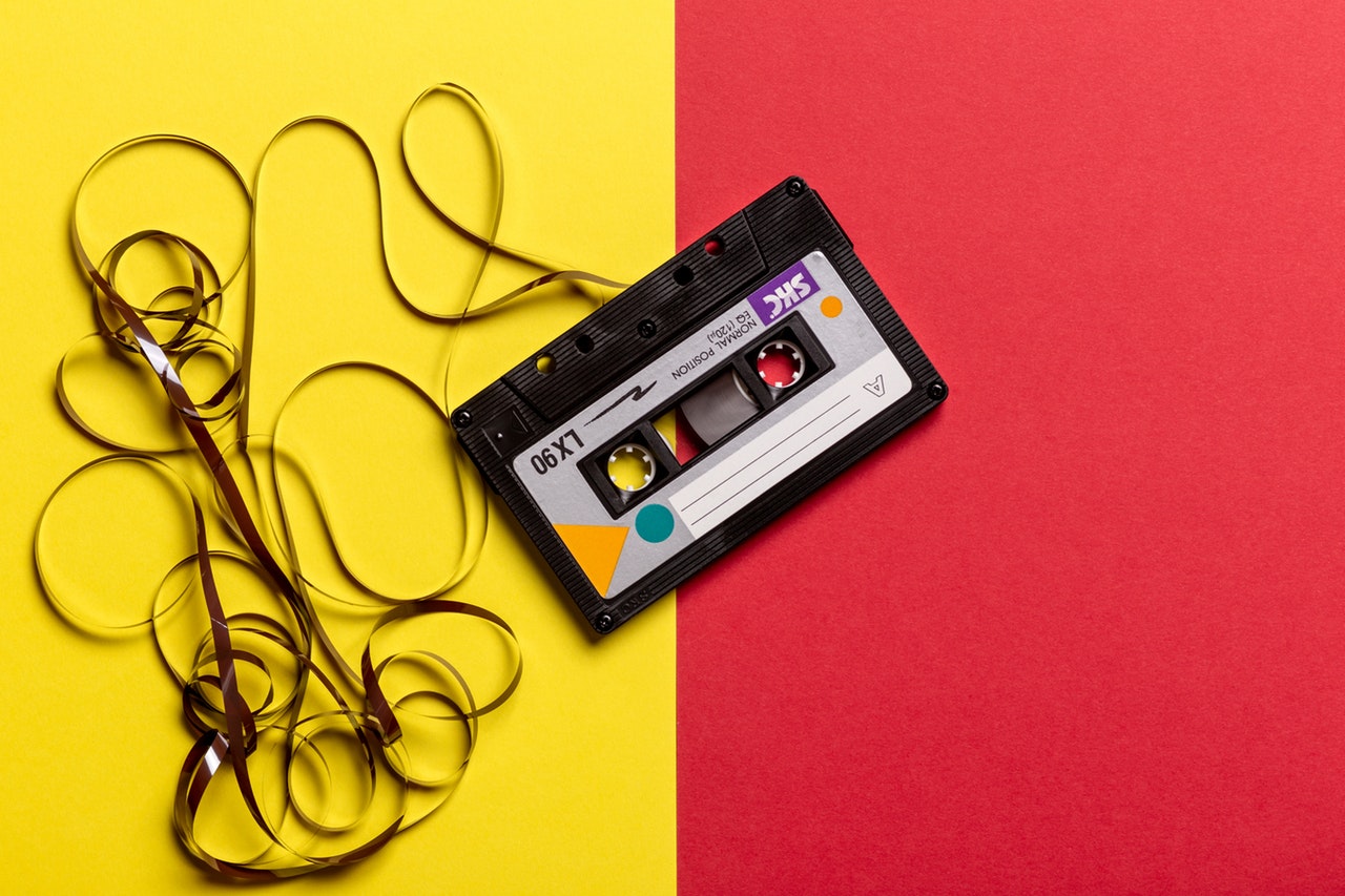 black-cassette-tape-on-top-of-red-and-yellow-surface-1626481